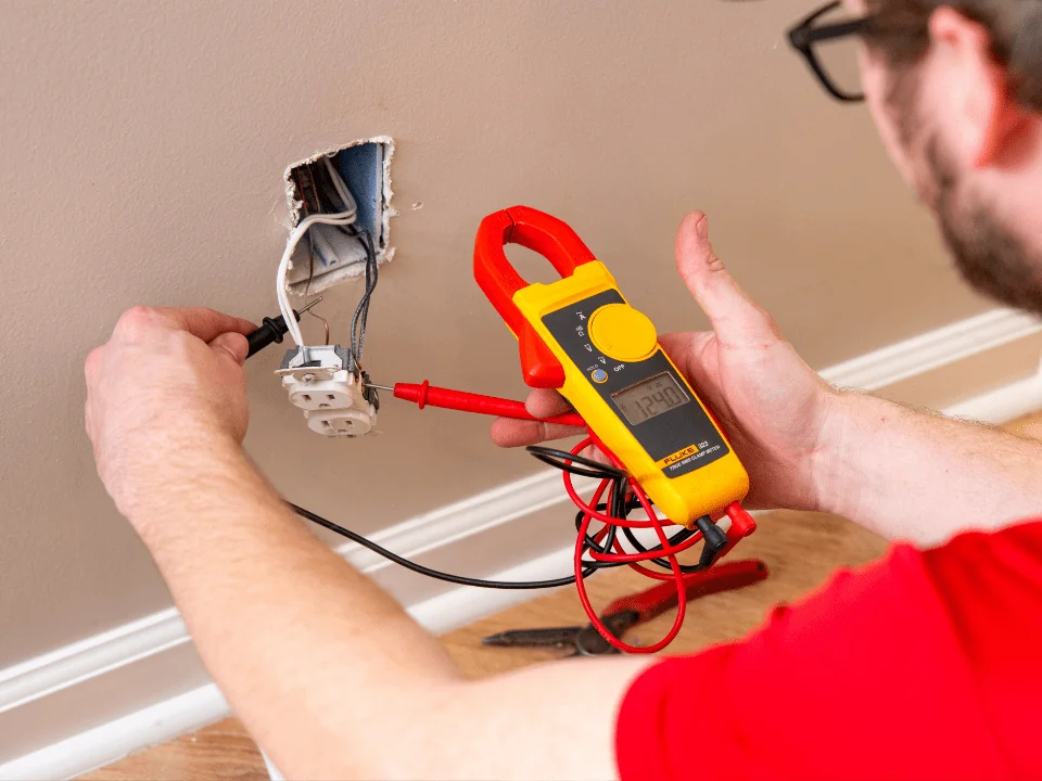Electrician using a multimeter for outlet repair